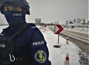 umundurowany policjant stoi przy zaśnieżonej drodze