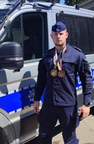 policjant na tle radiowozu wraz medalami
