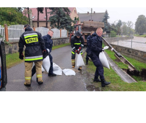 Zdjęcie przedstawia trzech mundurowych, stojących na drodze.