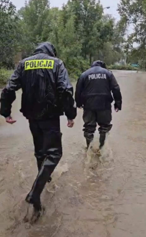 Zdjęcie przedstawia policjantów w woderach.