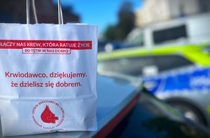 torebka z napisem, w tle radiowóz