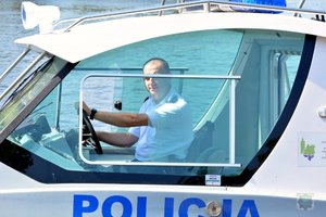 policjant siedzi za sterami łodzi motorowej