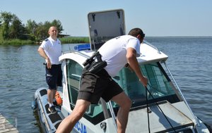 dwóch policjantów ogniwa wodnego wchodzi do łodzi motorowej