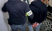policjant ubrany po cywilu prowadzi zatrzymanego