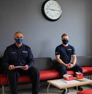 2 policjantów siedzi obok siebie i wypełniają formularz przed oddaniem krwi