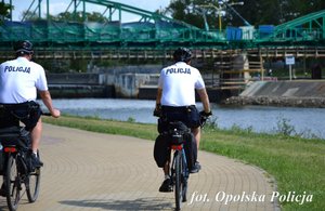 widok z tyłu na 2 jadących rowerami policjantów