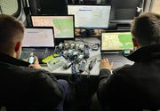 dwóch policjantów siedzi naprzeciwko monitorów komputerowych